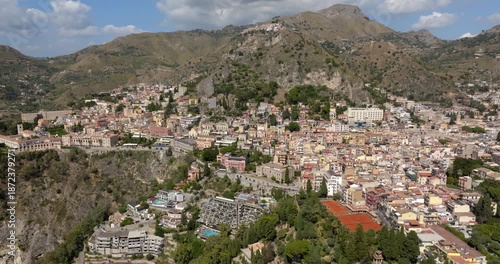 Panoramic aerial view of Taormina, in the province of Messina, Sicily, Italy. It is a picturesque town nestled between the Sicilian Nebrodi Mountains and the Mediterranean Sea. It's a summer morning.