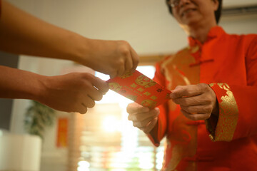 Chinese New Year tradition captured in detail, showing the meaningful giving of a red envelope between family members at home