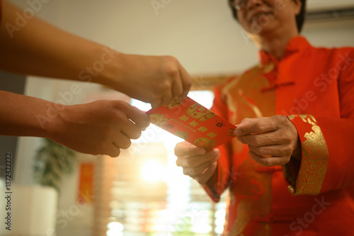 Chinese New Year tradition captured in detail, showing the meaningful giving of a red envelope between family members at home