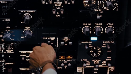 Close-up of airplane pilot operating controls in cockpit at night