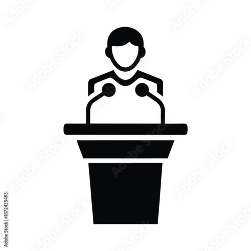 A faceless figure stands delivering a speech at the podium with two microphones present