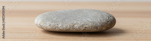 weathered sea pebble lies flat wooden table serving textured backdrop minimalist studio setup soft natural