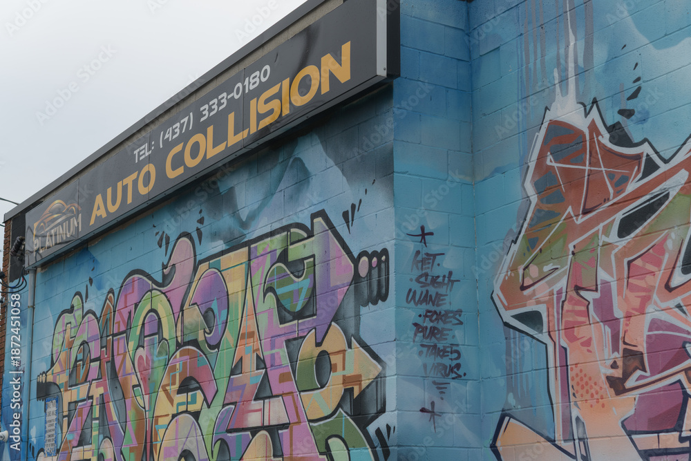 Obraz premium exterior wall with street art and sign of Platinum Auto Collision located at 2 Cariboo Av, Toronto (shown here side facing Osler St)