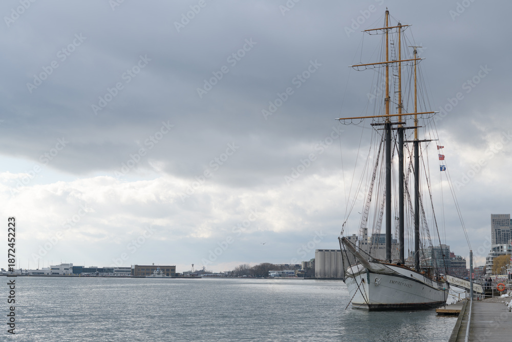 Obraz premium Empire Sandy, a historic 200-foot three-masted schooner based in Toronto, originally built in 1943 as a British WWII deep-sea tugboat, later converted in the 1980s into a sail-rigged passenger ship