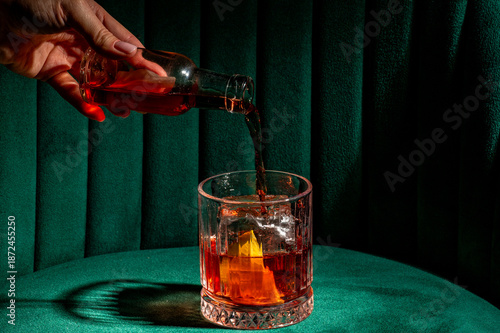Foto Person pouring a classic Negroni cocktail with gin, Campari, and sweet vermouth