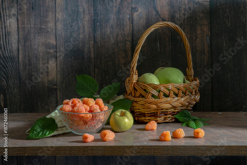 A delicious still life with orange raspberries and green apples in a basket