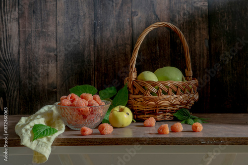 A delicious still life with orange raspberries and green apples in a basket