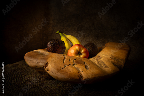 Photos Artistic still life of  fruit in a rustic wooden bowl, moody chiaroscuro lighting