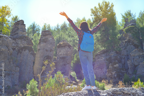 A woman tourist with a backpack on her back walks through the ancient city of Selga, admiring the wonderful nature and wonderful rocks. Turkey, Antalya
