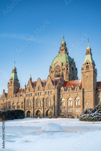 Das neue Rathaus der Landeshauptstadt Hannover im Winter bei blauem Himmel und Sonnenschein, im Vordergrund der Maschteich mit Eis und Schnee (Hochformat)