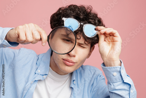 Fotografie Squinting young man with magnifying glass and glasses poor eyesight vision conce