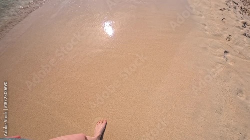 PORTOCOLOM, MALLORCA, SPAIN - OCTOBER 25, 2025: Person walks on the sandy beach, wide shot, just feet in frame. The Mediterranean Sea is seen in the background. Can be used for slow-motion.