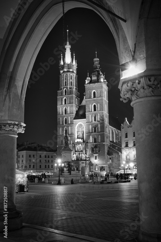 Obraz na plátně Czarno-białe zdjęcie Rynku Głównego w Krakowie, ukazujące historyczną architekturę, brukowane ulice i atmosferę zabytkowego centrum miasta
