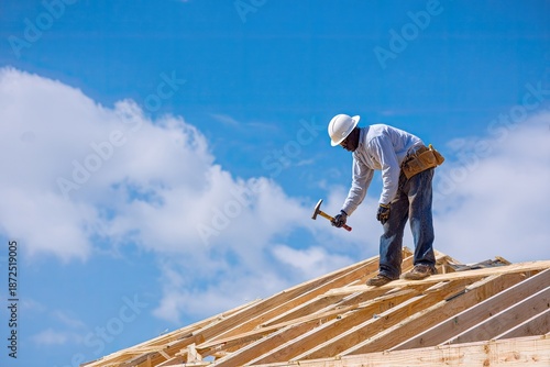 Wallpaper Mural Construction worker hammering wood on rooftop against vibrant blue sky Torontodigital.ca