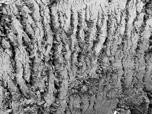 High-detail black and white close-up of rough cracked concrete surface with vertical grooves and irregular texture. Monochrome industrial background with strong contrast and raw material feel.
