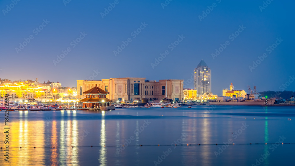 Fototapeta premium Illuminated waterfront buildings at twilight