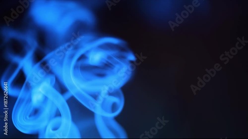 Abstract blue smoke slowly rises and swirls creating mesmerizing shapes