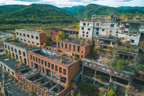 An abandoned mining and processing facility sits in disrepair, with crumbling structures overtaken by nature.