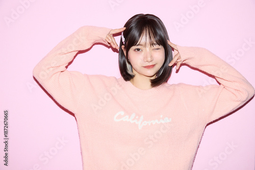 ピンク背景でキュートなポーズをする若い女性のポートレート