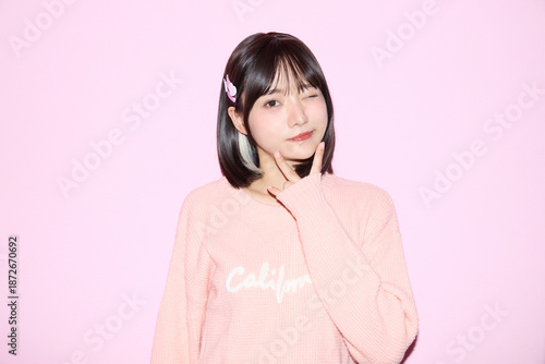 ピンク背景でキュートなポーズをする若い女性のポートレート