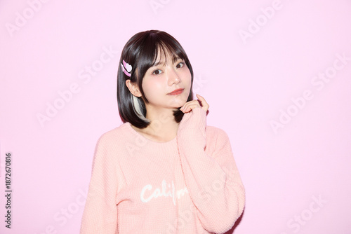 ピンク背景でキュートなポーズをする若い女性のポートレート