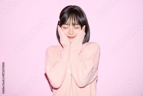 ピンク背景でキュートなポーズをする若い女性のポートレート