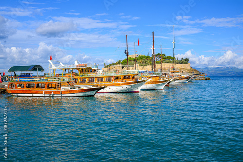 Tableau sur toile Colorful and historic tour boats line the pier on Pigeon Island with the Kusadasi Castle behind, in Kusadasi, Turkey