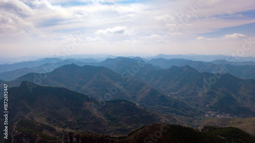 Autumn red leaves blanket the mountains, creating a continuous layer of forest colors. The aerial view reveals a continuous range of layered mountain scenery