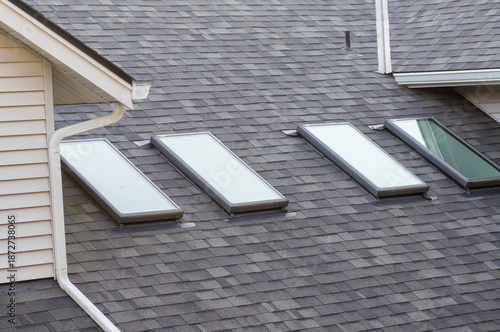 Closeup of attic window on house roof top covered with shingles