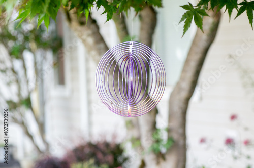 A spinning decorative ornament hanging from a tree in the backyard.