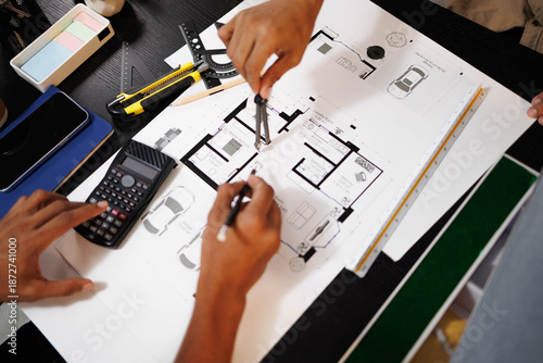 Wallpaper Mural 
Two people are working on a house plan design. They are using various tools, working with the plan, and reviewing a house model to verify the accuracy of their work in the workplace.

 Torontodigital.ca