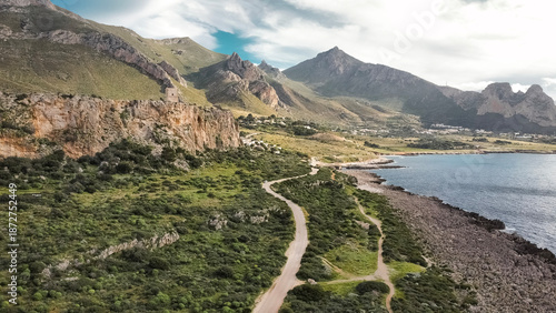 Aerial View Of San Vito Lo Capo In Sicily: Coastal Road Winding Through Green Mediterranean Landscape Toward Southern Rock Climbing Cliffs And Limestone Mountains