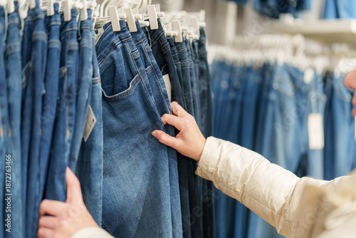 Принти на полотні Person selecting denim jeans in a clothing store during the day