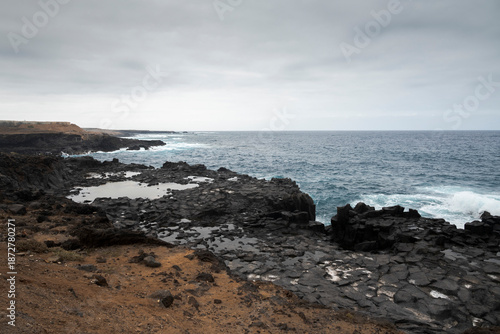 Volcanic rock pools and rugged cliffs meet the Atlantic Ocean under a cloudy sky in Los Silos, Tenerife, Spain, capturing the island’s raw and dramatic coastal beauty