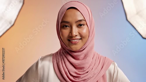 Woman wearing pink hijab smiling with studio lights on sides