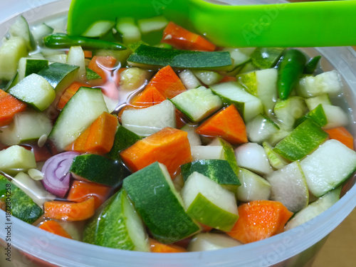 A close-up shot of a plastic bowl filled with pickles.
