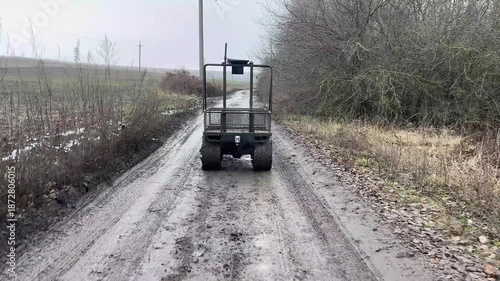 A military ground-based robotic complex drives along the frontline road along the forest belt. Robots that deliver goods to the line of contact. A machine that is controlled remotely.