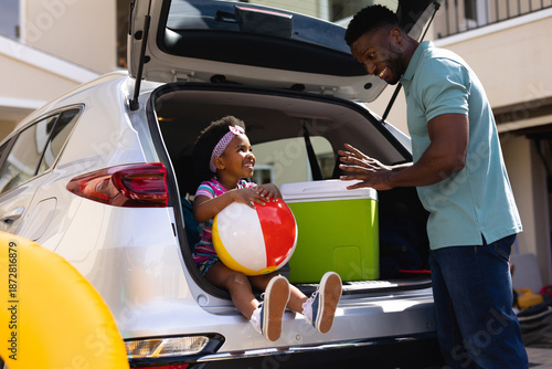 African american father talking to daughter sitting in the back of the car