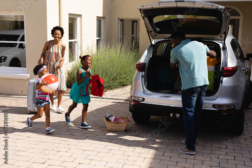 African american father putting all the luggage in the back of the car