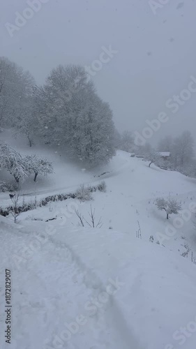 View of a village under snow in French alps by winter on a snowing day