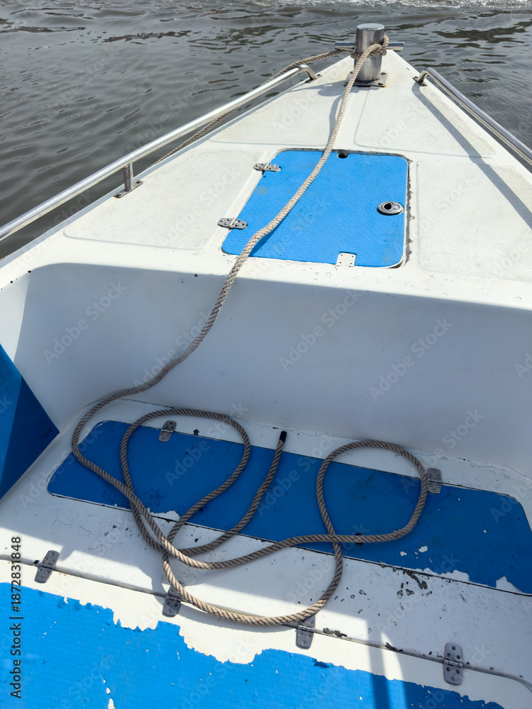 Fototapeta premium A boat with a blue and white seat and a rope tied to the boat