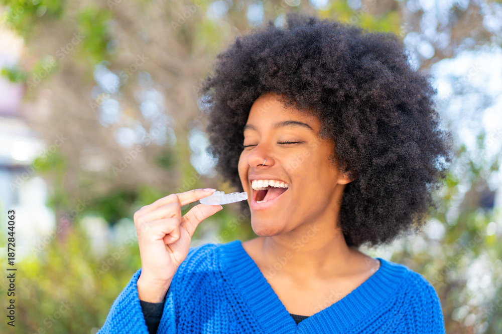 Fototapeta premium African American girl at outdoors holding invisible braces