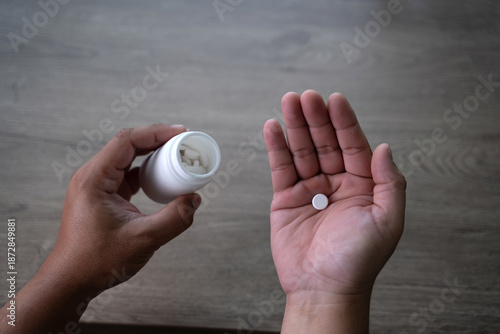 Foto Close-up of hands pouring pills into palm from a medicine bottle, representing m