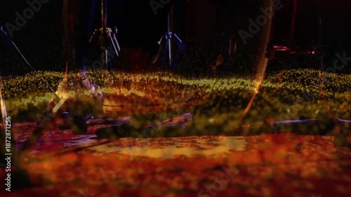 drum tech adjusting hardware on stage, with glowing particle wave showcasing music technology