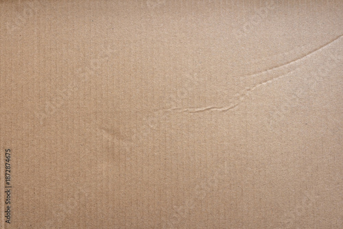 Detailed close up of a light brown corrugated cardboard surface showing vertical texture and slight creases