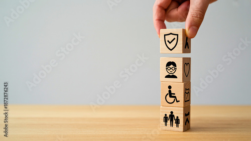 Hand stacks blocks with icons for security, disability, and family support, symbolizing comprehensive social welfare and future planning