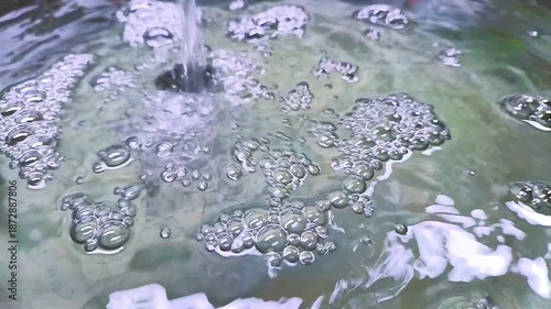 A bubbling water surface is shown with foam and visible turbulence patterns forming across the liquid. Water pollution concept