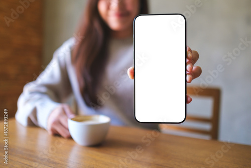 Wallpaper Mural Mockup image of a woman holding and showing a mobile phone with blank white screen while drinking cafe Torontodigital.ca