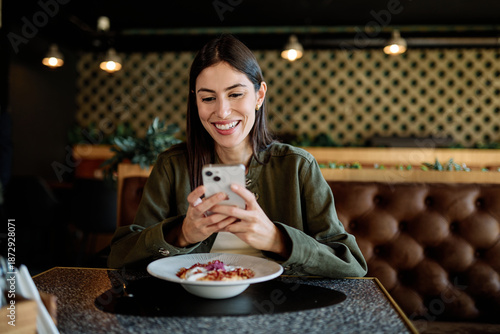 Wallpaper Mural Young woman enjoying eating lunch and using a mobile phone at restaurant Torontodigital.ca