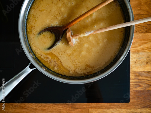 Bild auf Leinwand Gravy sauce in frying pan on electric stove. Top view